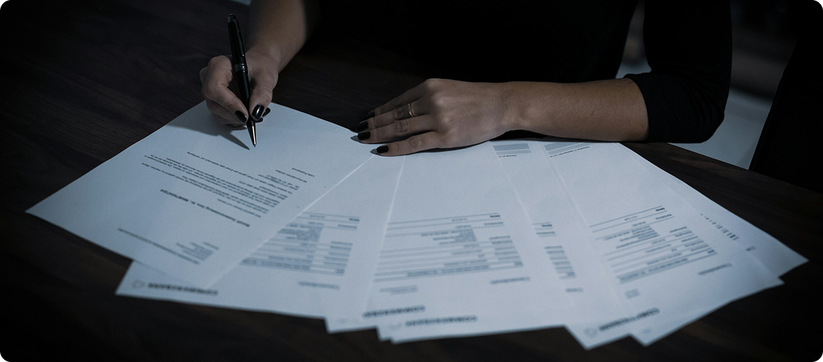 Close-up of hands signing trademark renewal documents in a professional setting